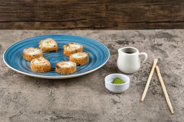 Mavi bir tabak soya soslu tempura rulo ve taş yüzeyinde wasabi. Yüksek kalite fotoğraf