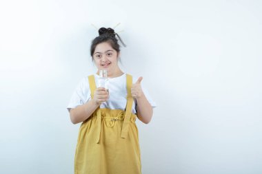 Genç ve güzel kız model ayakta ve beyaz duvara karşı cam şişe tutuyor. Yüksek kalite fotoğraf