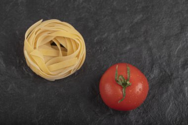 Siyah yüzeyde taze domatesli çiğ tagliatelle yuvaları. Yüksek kalite fotoğraf