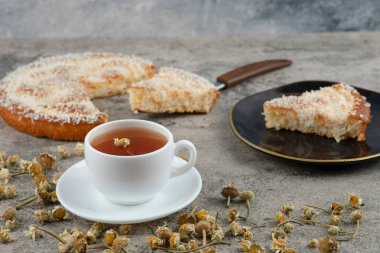 Lezzetli bir pastanın siyah tabağı ve arka planda beyaz bir fincan sıcak çay. Yüksek kalite fotoğraf