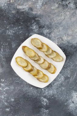 Dilimlenmiş salatalık turşusuyla dolu beyaz tabak mermer arka planda. Yüksek kalite fotoğraf