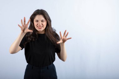 Beyaz arka planda kızgın bir ifadeyle duran esmer bir kızın fotoğrafı. Yüksek kalite fotoğraf