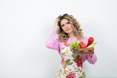 Önlüklü, bir kutu taze sebzeyle poz veren güzel bir kadın. Yüksek kalite fotoğraf