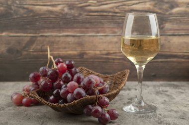 Kırmızı üzüm sepeti ve mermer masada bir kadeh şarap. Yüksek kalite fotoğraf