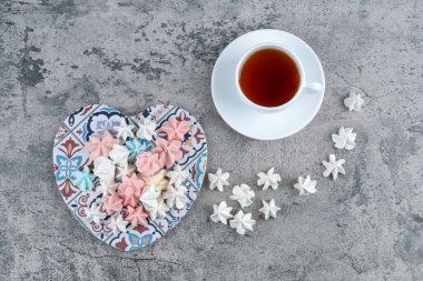 Bir demet renkli krema şekeri, kalp şeklinde süs taşı ve bir fincan çay. Yüksek kalite fotoğraf