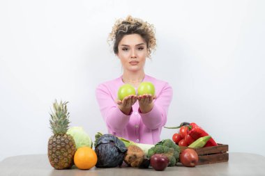 Elinde taze elmalarla masada oturan güzel bir ev hanımı resmi. Yüksek kalite fotoğraf