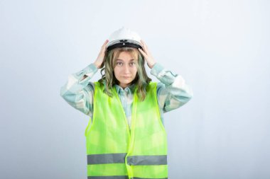 Beyaz arka planda duran yeşil yelekli genç inşaat işçisinin fotoğrafı. Yüksek kalite fotoğraf