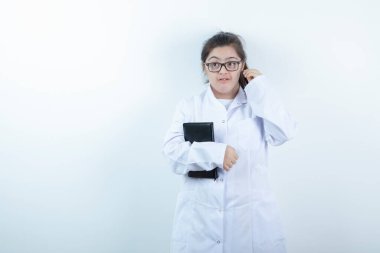 Doktor üniformalı genç bir kız ayakta ve elinde not defteri var. Yüksek kalite fotoğraf