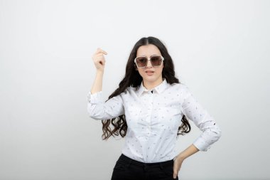 Ayakta duran ve gözlüklerle poz veren şık bir genç kadın. Yüksek kalite fotoğraf