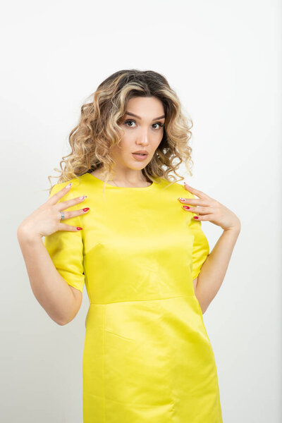 Blonde curly hair woman in yellow dress standing over white. High quality photo