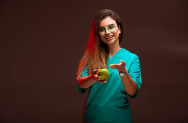 Genç bir kız elinde yeşil bir elma sunuyor. Yüksek kalite fotoğraf