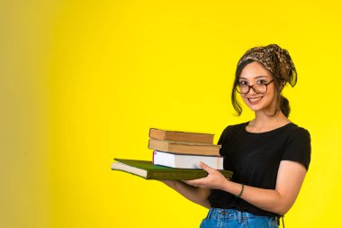 Gözlüklü genç kız kitaplarını tutuyor ve kendinden emin hissediyor. Yüksek kalite fotoğraf