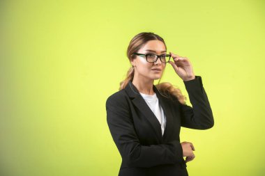 Siyah ceketli ve gözlüklü iş kadını kendinden emin görünüyor. Yüksek kalite fotoğraf