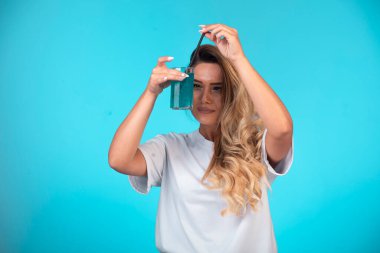 Beyaz gömlekli genç kız elinde bir bardak mavi kokteyl tutuyor ve bakıyor. Yüksek kalite fotoğraf