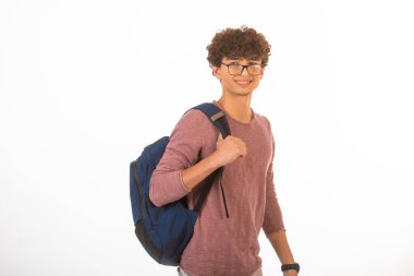Omzunda sırt çantasıyla gözlüklü kıvırcık saçlı çocuk gülümsüyor. Yüksek kalite fotoğraf