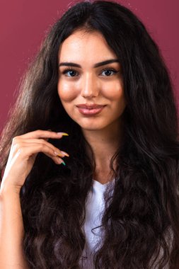 Uzun ve kıvırcık saçlı esmer kız sonbahar makyajını destekliyor ve gülümsüyor. Yüksek kalite fotoğraf