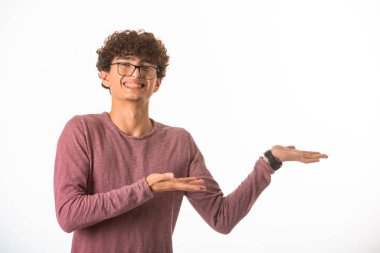 Gözlüklü kıvırcık saçlı çocuk bir şey gösteriyor ve gülüyor. Yüksek kalite fotoğraf