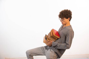 Kıvırcık saçlı, iyimser gözlüklü bir çocuk ancak ağır kitaplar tutuyor. Yüksek kalite fotoğraf