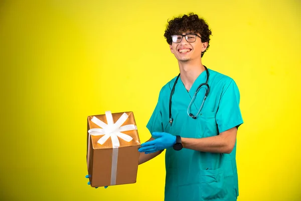 Lockiger Junge Arztuniform Und Handmasken Der Eine Geschenkbox Der Hand — Stockfoto