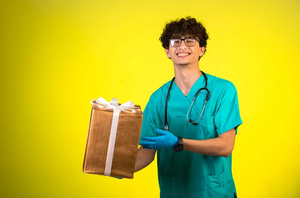 Lockiger Junge Arztuniform Und Handmasken Der Eine Geschenkbox Der Hand — Stockfoto