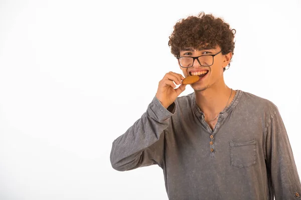 Kıvırcık Saçlı Iyimser Gözlüklü Çocuk Kurabiye Tadıyor Gülümsüyor Yüksek Kalite — Stok fotoğraf