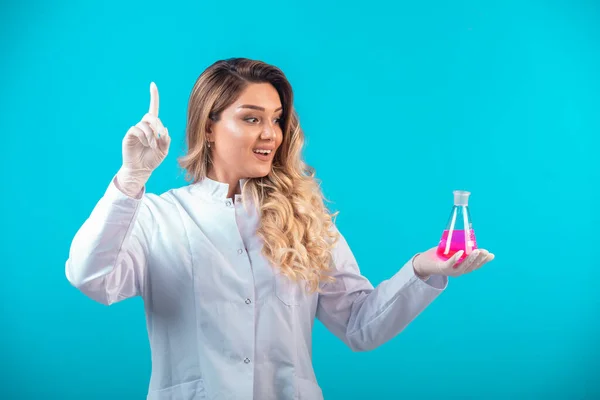 ピンクの液体で化学フラスコを保持し 注意を要求する白い均一な看護師 高品質の写真 — ストック写真