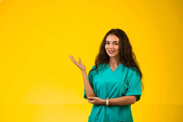 Female nurse opens hands and and points to something. High quality photo