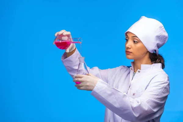 若い看護師は化学液体を1つのフラスコから別のフラスコに置きます 高品質の写真 — ストック写真