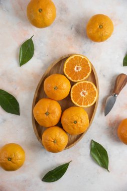 Ahşap tabağın üzerinde yarım veya yarım Clementine mandalinası olan dikey bir fotoğraf. Yüksek kalite fotoğraf