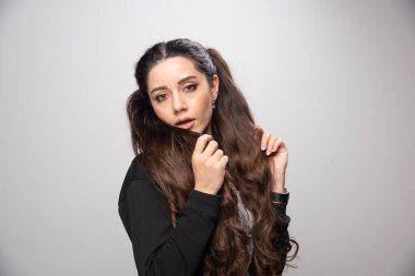 Siyah kazaklı, uzun saçlı kız kameraya bakıyor. Yüksek kalite fotoğraf