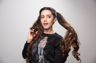 Saçlarını gri arka planda tutan genç ve güzel bir kadın. Yüksek kalite fotoğraf