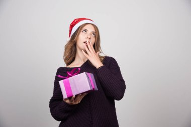 Noel Baba şapkalı genç bir kadın elinde bir hediye kutusu tutuyor. Yüksek kalite fotoğraf