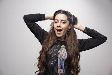 Gri arkaplandaki kameraya bakan sıradan kazaklı genç bir kadın. Yüksek kalite fotoğraf