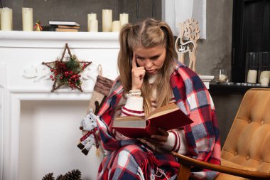 Sarışın kadın şöminenin yanında ilginç kitaplar okuyor. Yüksek kalite fotoğraf