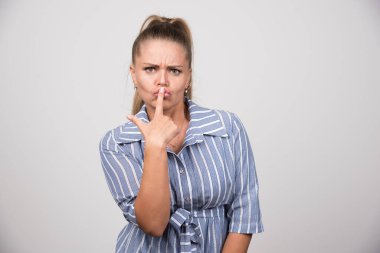 Gri arka planda sessizlik işareti veren genç bir kadın. Yüksek kalite fotoğraf