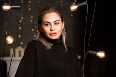 Lambaların yanında duran koyu renk kazaklı mutlu bir kadının portresi. Yüksek kalite fotoğraf