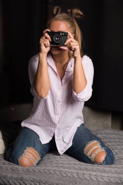 Genç bir kadın karanlık arka planda kamerayla fotoğraf çekiyor. 