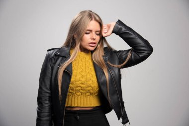 Siyah deri ceketli sarışın kız profesyonel ve sıkı bir duruş sergiliyor. Yüksek kalite fotoğraf