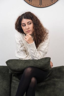 Koyu yeşil kanepesinde elinde yastıkla oturan genç bir kadın. Yüksek kalite fotoğraf