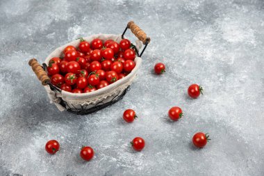 Kırmızı kiraz domatesleri mermer arka planda bir sepette. Yüksek kalite fotoğraf