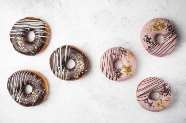 Beyaz arka planda birçok çikolata ve pembe çöreğin düz manzarası var. Yüksek kalite fotoğraf