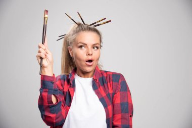 Sarışın sanatçı fırça tutuyor, onlara bakıyor ve eğleniyor. Yüksek kalite fotoğraf