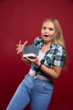 Sarışın kız ya bir hediye kutusu sunuyor ya da diğerleriyle paylaşıyor. Yüksek kalite fotoğraf