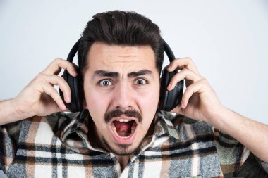 Kulaklıklı yakışıklı bir adamın ayakta durup şarkı dinlediği bir görüntü. Yüksek kalite fotoğraf