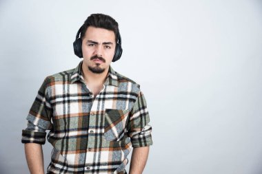 Kulaklıklı yakışıklı bir adamın beyaz duvardan kızgın bakışları. Yüksek kalite fotoğraf