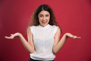 Gülümseyen kadın ellerini kırmızı arka planda gösteriyor.