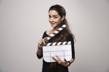 Film yapımcısı bir kız elinde boş bir el çırpma tahtası tutuyor ve pozitif görünüyor. Yüksek kalite fotoğraf