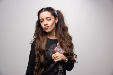 Gri arka planda baş parmak gösteren genç bir kızın portresi. Yüksek kalite fotoğraf