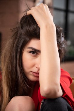 Kırmızı bluzlu genç bir kadın model oturuyor ve poz veriyor. Yüksek kalite fotoğraf