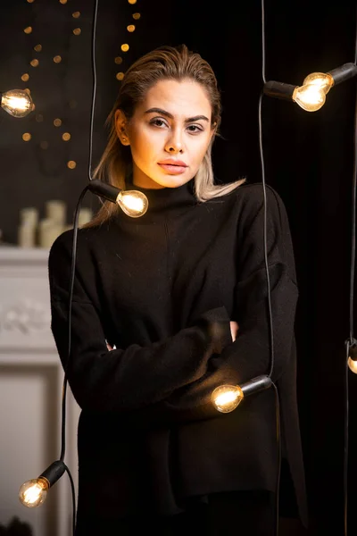 ランプの近くに立って暗いセーターのカメラを見てきれいな女性の肖像画 高品質の写真 — ストック写真
